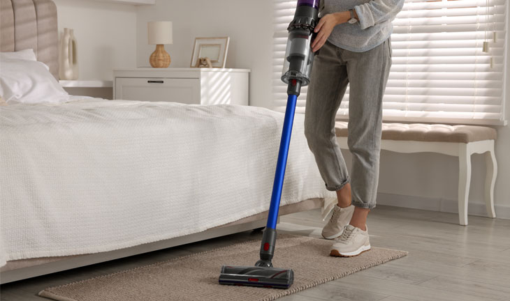 Resident vacuuming a bedroom as part of an apartment cleaning routine